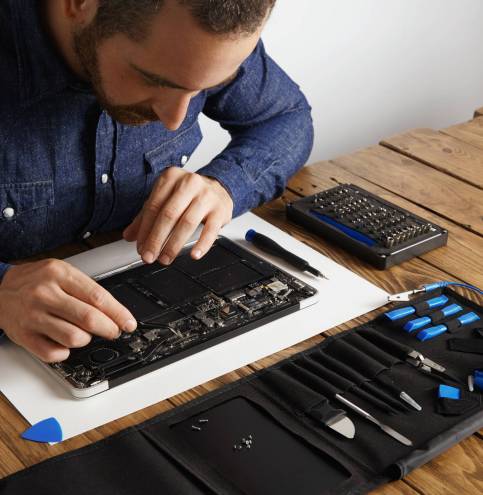 Master uses angled esd tweezers to remove dust from electronic boards of broken slim computer laptop to fix it and make to work again